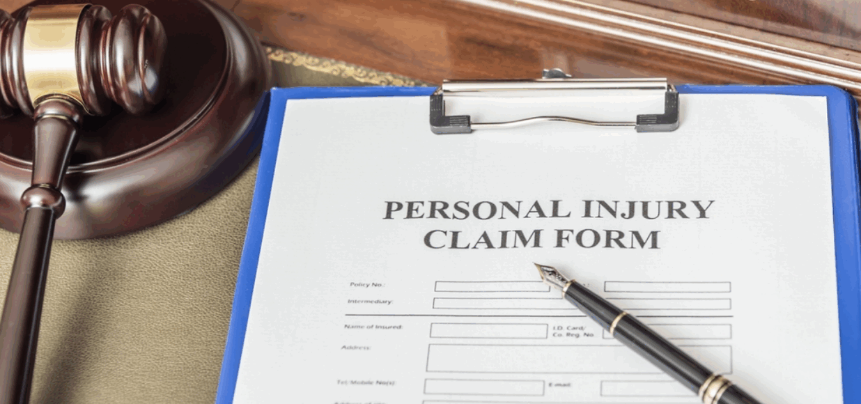 A personal injury claim form on a clipboard with a pen placed on top, next to a judge’s gavel, symbolizing legal action and personal injury lawsuits.