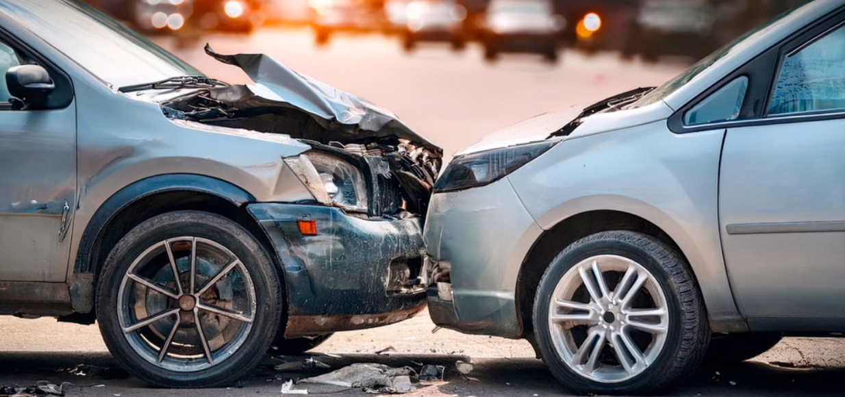 Two cars with severe front-end damage after a head-on collision in the street, illustrating the aftermath of a car accident involving insurance disputes.