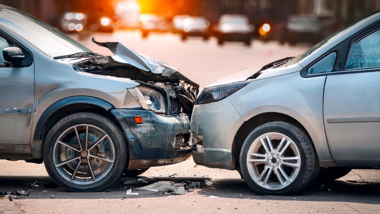 Two cars with severe front-end damage after a head-on collision in the street, illustrating the aftermath of a car accident involving insurance disputes.