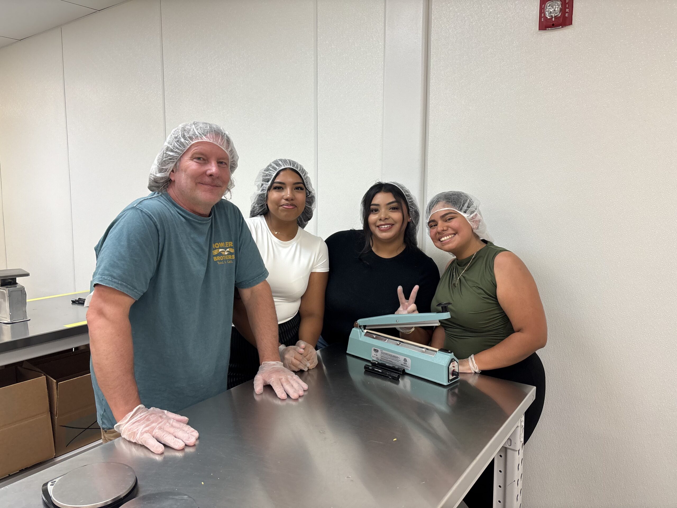 Four Robert J. DeBry and Associates staff members packing food at a Utah Food Bank table
